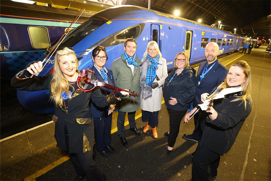 Lumo representatives next to two violinists at Glasgow station