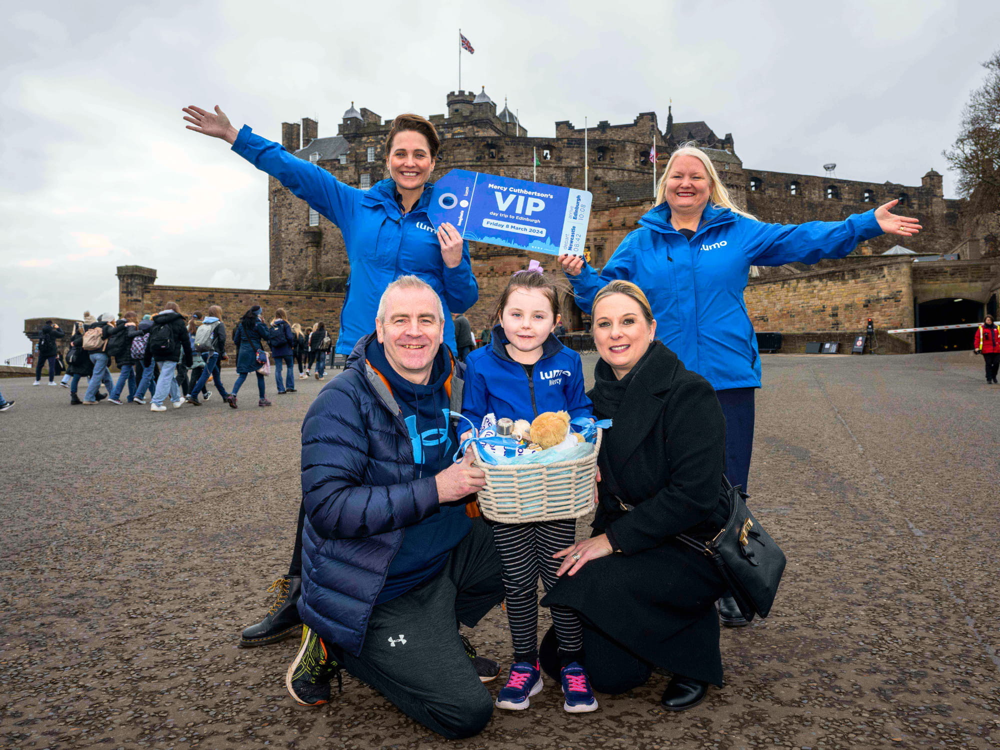 lumo VIP winner passenger with her family and two train ambassadors in front of Edinburgh castle