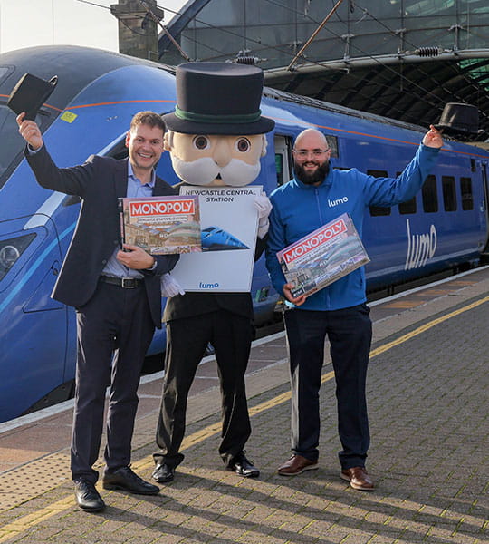 Martijn Gilbert, Managing Director of Lumo, and David Fox, Planning and Performance Manager at Lumo, posing next to Mr Monopoly at Newcastle Station