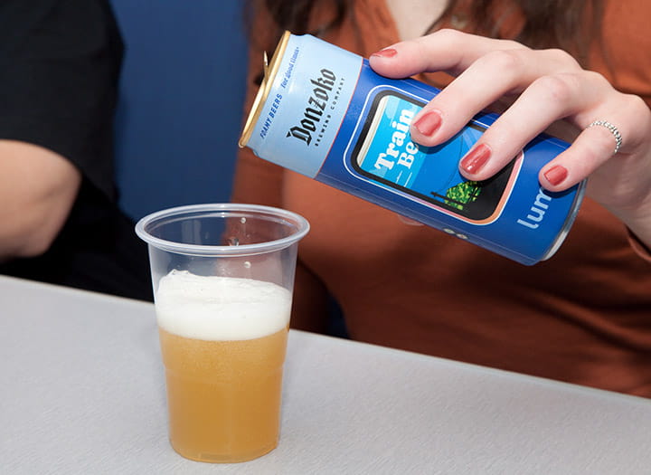 customer pouring a can of train beer on a glass